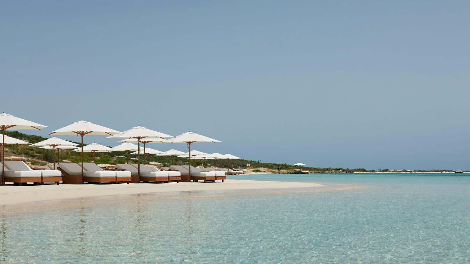 Luxury beach club sunbeds and parasols by clear water on Al Maha Island, Qatar