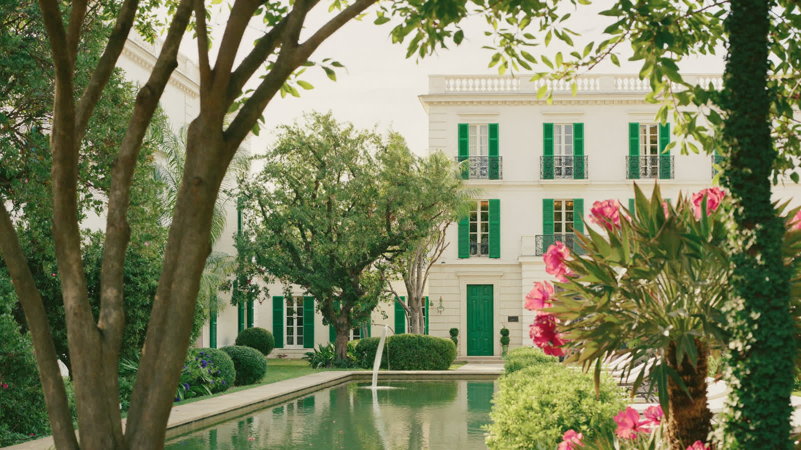 French colonial hotel courtyard with white facade and green shutters, Hanoi