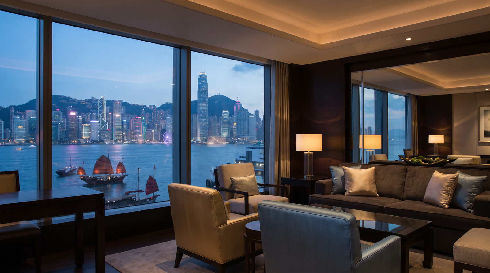 Luxury hotel suite with floor-to-ceiling windows over Victoria Harbour at dusk, Hong Kong