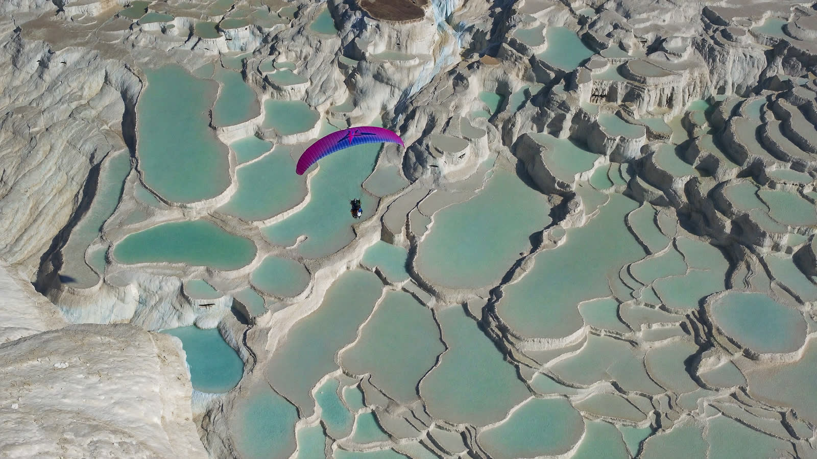 Paraglider above the white travertine terraces of Pamukkale