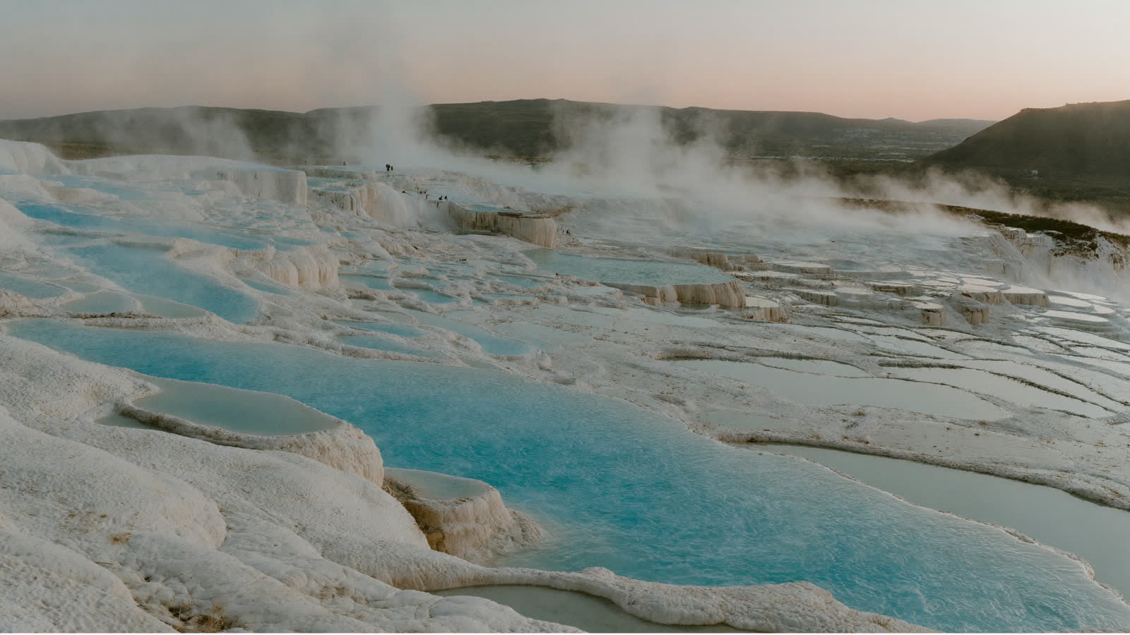 White travertine terraces with turquoise thermal pools at sunset, Pamukkale