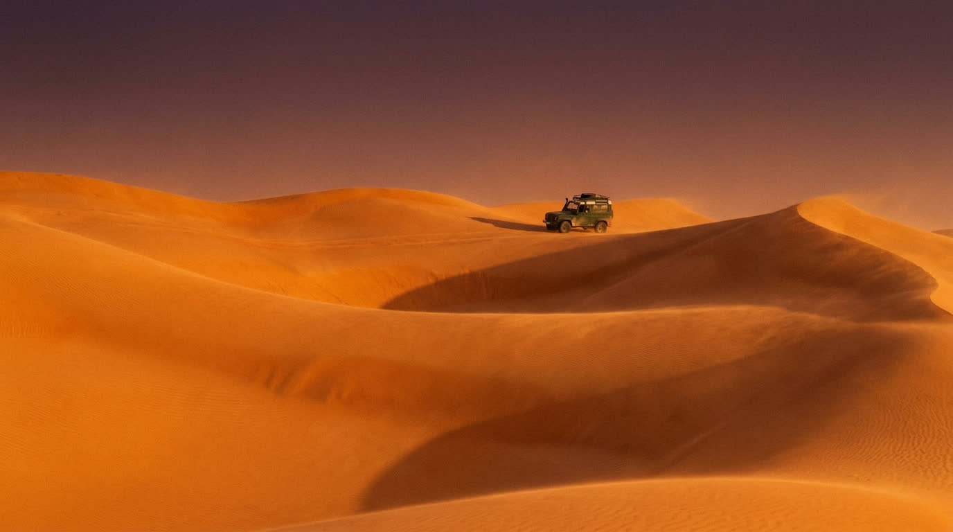 Immense orange dunes of the Empty Quarter near Dhofar at sunset with a distant 4x4