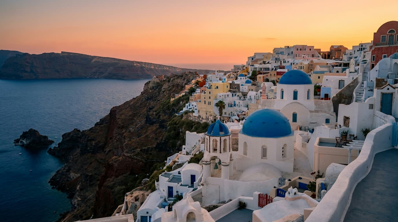 Whitewashed houses and blue domes of Oia cascading down Santorini's caldera cliff at golden hour