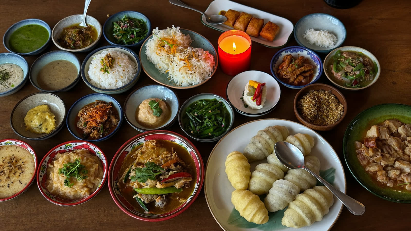 Sri Lankan rice and curry spread of many small dishes, candlelit table